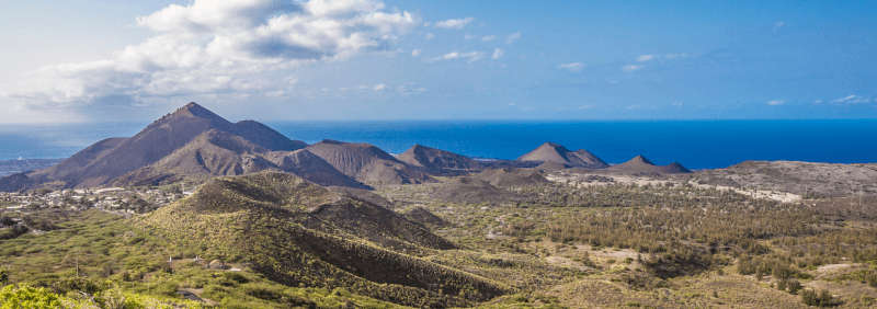 Photo of Ascension Island, showing green mountains and blue water.