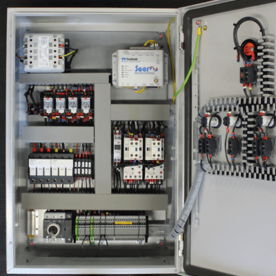 An open T-T pump control panel showing wiring and a remote monitoring SEER monitoring unit.