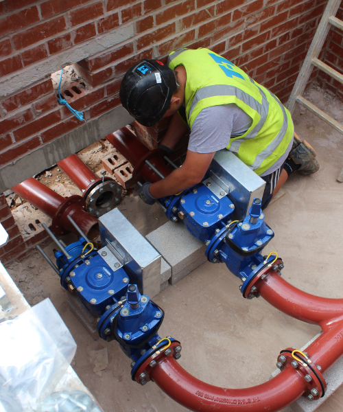 A T-T Engineer installing pipework and valves on-site.