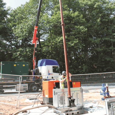 A construction site showing a T-T site engineer installing a package pumping station, with a crane in the background.