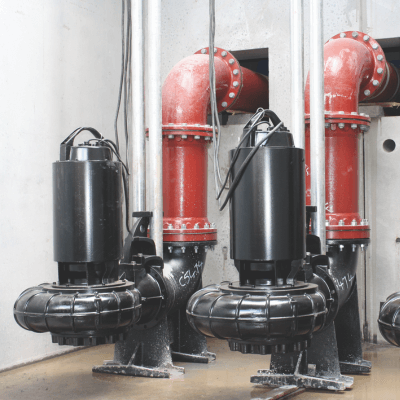 Two black pumps connected to red pipes inside a pumping chamber.